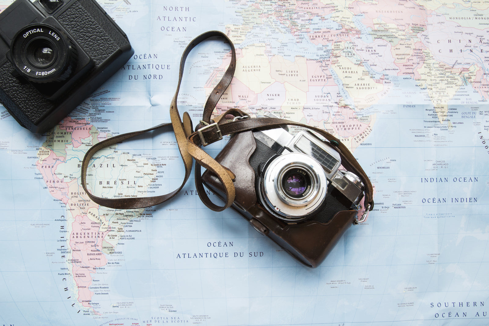 Box DIY Siya Vibes posée sur une carte du monde et un appareil photo vintage